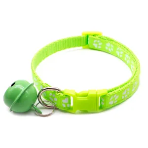 Green pet collar detail showing white paw print pattern, quick-release buckle and green bell.