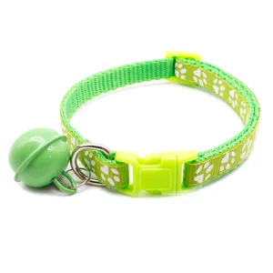 Close-up view of the green pet collar showing cute white paw print patterns and a matching bell detail.