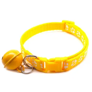 Close-up detail of yellow pet collar with cute white paw print, bell, and secure buckle.