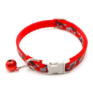 Close-up detail of red camouflage pet collar with white buckle, metal D-ring and red bell.