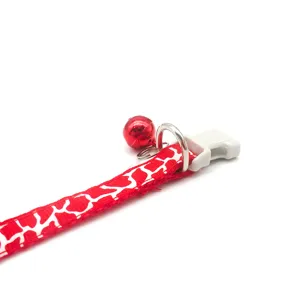 Detailed close-up shot of red and white cracked pet collar strap with metal bell and buckle.