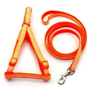 Orange plaid pet dog harness and leash set detail, adjustable vest style strap with metal hook.