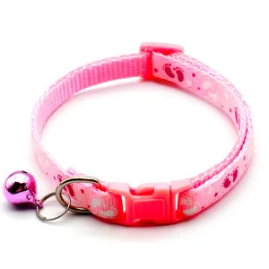 Close up of a pink pet collar with cute paw prints, plastic buckle and a shiny bell detail.