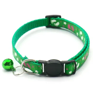Green pet collar detail shot, featuring paw print pattern, metal bell and quick release buckle.