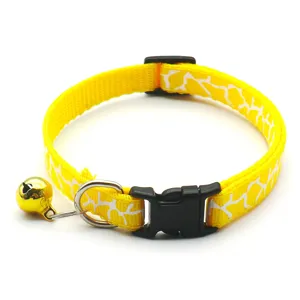 Detailansicht eines gelben Haustier Katzenhalsbandes mit weißem Muster und goldener Glocke.
