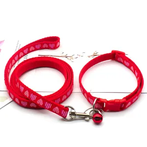 Detail shot of red heart printed pet leash and collar, featuring metal hardware and bell.