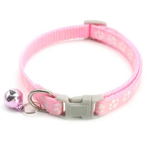 Detailed shot of pink pet collar with white paw prints, grey buckle, and a cute bell.