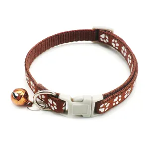 Brown nylon pet cat collar with white paw print pattern, plastic buckle, metal ring and bell.
