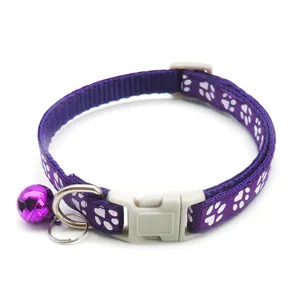 Detailed view of purple nylon pet cat collar with cute white paw print pattern and bell.