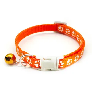 Orange pet collar detail with cute white paw prints, safety buckle, and a gold bell.
