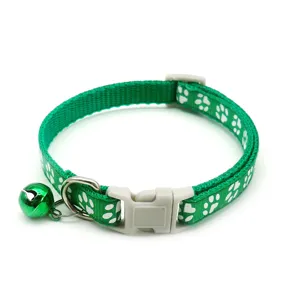 Green pet cat collar with cute white paw print, bell and buckle. Detail view of safety accessory.