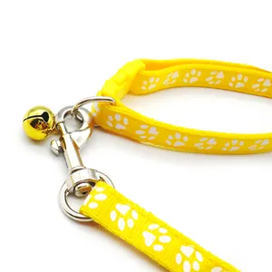 Set guinzaglio e collare per cani e gatti giallo con motivo impronta di zampa e campanello.