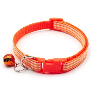 Orange plaid pet collar detail, fabric neck strap, plastic buckle, and bell decoration.