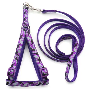 Dettaglio imbracatura per animali mimetica viola con cinghie regolabili e gancio metallico.