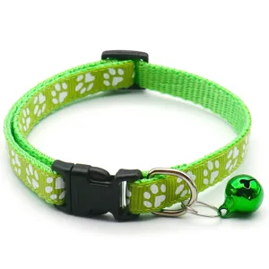 Gros plan d'un collier pour animaux vert avec motif d'empreintes, boucle et clochette.