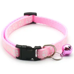 Détail de collier pour animal de compagnie rose avec motif patte, anneau en métal et clochette.