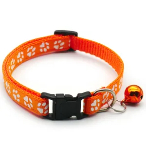 Détail de collier pour animal orange avec empreintes de pattes, boucle et petite cloche.