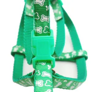 Green pet harness detail showing nylon fabric, white bone pattern and secure plastic buckle.