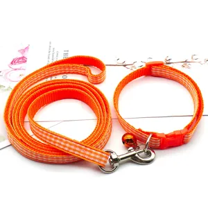 Orange plaid pet leash and collar set detail view, featuring metal clasp and bell.