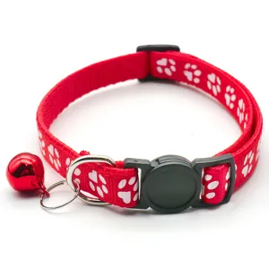 Red pet collar close-up, paw print pattern, metal D-ring, and red jingle bell.