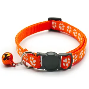 Detail view of adjustable orange pet collar featuring white paw prints, metal bell and buckle.