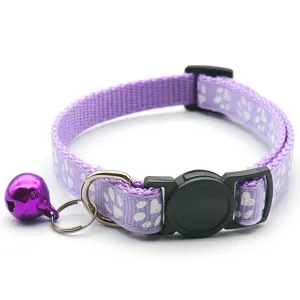 Detail view of adjustable purple pet collar with white paw prints and metal bell.