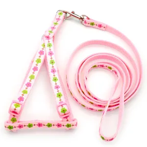 Detail view of pink floral pet leash and harness set, showing clear fabric print and metal hooks.
