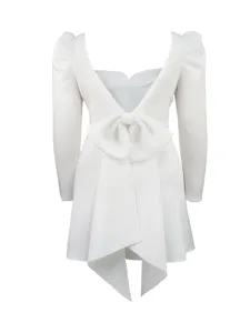 Detailaufnahme des eleganten weißen Langarm-Minikleids mit offenem Rücken und großer Schleife.