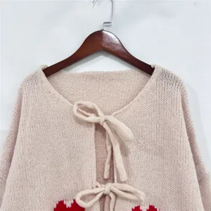 Gezellig gebreid damesvest detail met schattig hartjesmotief lange mouwen en strikstring.