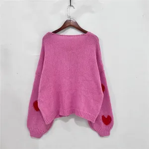 Roze gebreide trui detail toont zachte stoftextur en schattig rood hartje op de mouwontwerp.