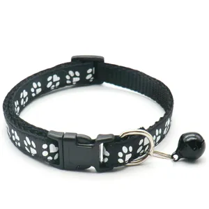 Gros plan détaillé du collier pour animal noir avec motif de pattes et cloche en métal.