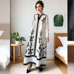 Detail view of the white long sleeve maxi dress with black floral ethnic print and V-neck.