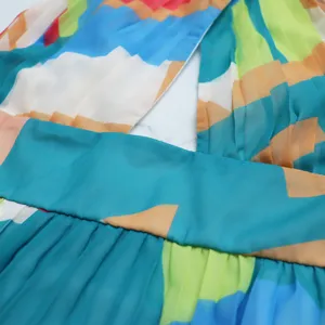 Close-up detail of sleeveless halter pleated chiffon dress with colorful abstract geometric print.