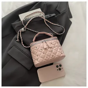 Detail view of the pink quilted mini box handbag, featuring chain strap and metal studs.