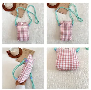 Detailed view of pink plaid mini phone pouch with mint green strap and button closure.