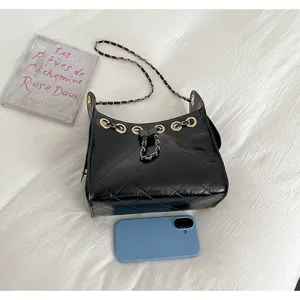 Detailed view of black quilted leather bucket bag with chain strap and drawstring design.