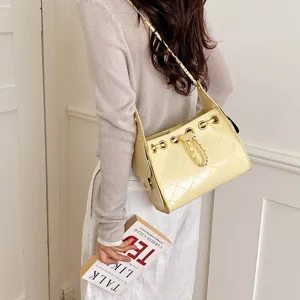 Chic yellow quilted bucket bag with chain strap and drawstring detail for stylish daily commute.