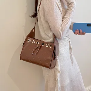 Brown quilted chain shoulder bag detail shot, showing unique grommet drawstring design and texture.
