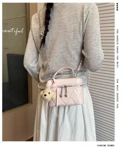 Pink quilted vanity crossbody bag with chic chain strap and cute plush bear pendant detail.
