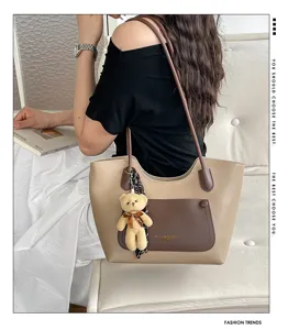 Close-up of stylish retro two-tone tote bag with cute bear pendant and spacious capacity.