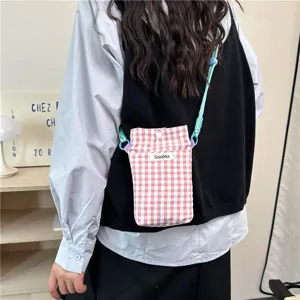 Detailed view of the pink plaid mini phone bag with green strap, showing close-up texture.
