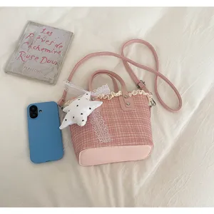 Detailed shot of a pink plaid bucket bag with cute lace trim and star pendant on white background.