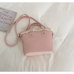 Detailed view of the pink leather handbag featuring delicate white lace trim and top handle.