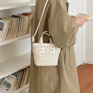 Close-up detail of stylish plaid bucket bag with chic lace trim and leather handles.