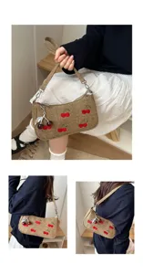 Detailed view of the casual shoulder bag with embroidered red cherry patterns and cute metal charm.