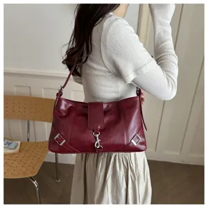 Vista dettagliata della borsa a tracolla rossa vintage indossata da una modella al chiuso.
