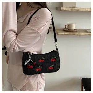 Stylish denim shoulder bag for women with cute embroidered cherry pattern and metal pendant.