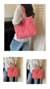 Gros-plan sur le sac cabas en toile à pois roses porté sur l'épaule avec une poche avant.