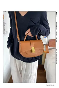 Primo piano di una borsa a tracolla marrone con serratura dorata in una stanza accogliente.