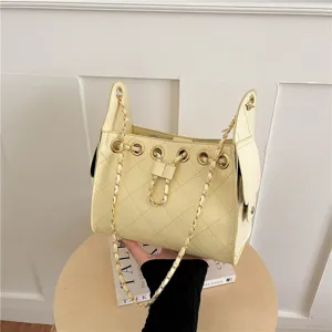 Detail view of yellow quilted chain bucket bag with drawstring closure and metal hardware.